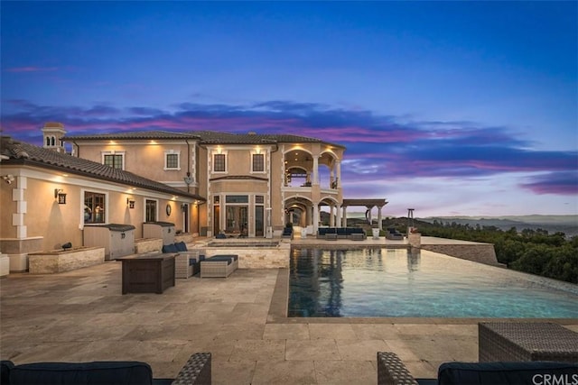 pool at dusk with a patio area