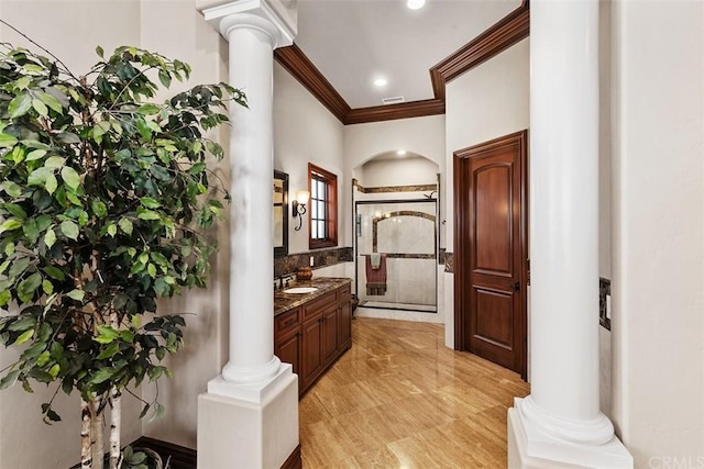 bathroom with tile floors, decorative columns, a shower with door, vanity, and crown molding