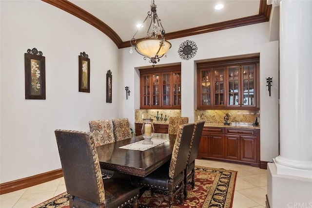 tiled dining area featuring crown molding, decorative columns, and vaulted ceiling