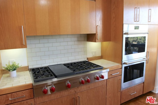 kitchen featuring backsplash, tile counters, and appliances with stainless steel finishes