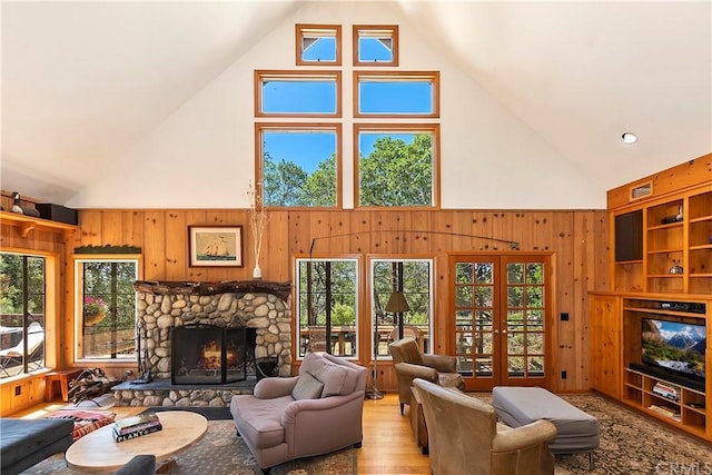 living room with a wealth of natural light, french doors, a stone fireplace, and high vaulted ceiling