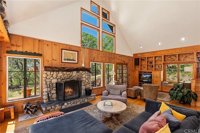 living room featuring high vaulted ceiling, hardwood / wood-style floors, built in features, and a stone fireplace