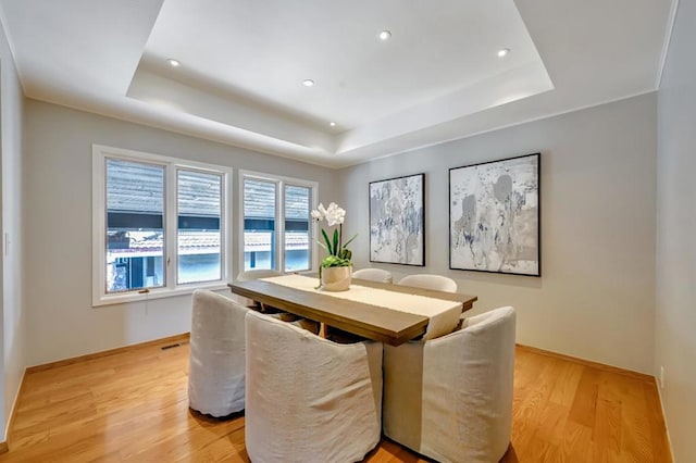 dining room with a raised ceiling and light hardwood / wood-style floors