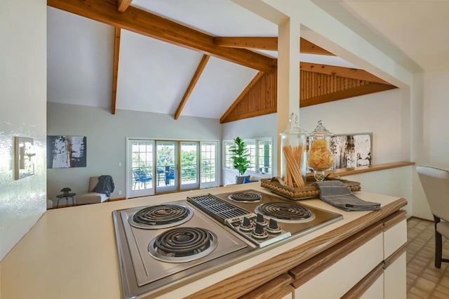 kitchen featuring stainless steel electric cooktop, high vaulted ceiling, white cabinets, and beam ceiling