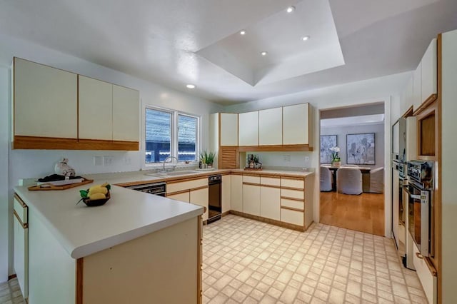 kitchen with light hardwood / wood-style flooring, black dishwasher, a raised ceiling, kitchen peninsula, and sink