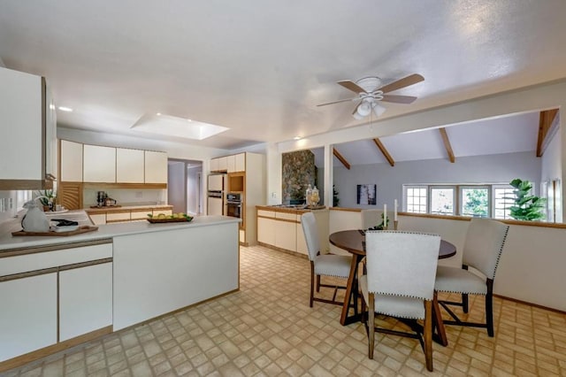 kitchen with ceiling fan, vaulted ceiling with beams, stainless steel oven, and light tile patterned floors