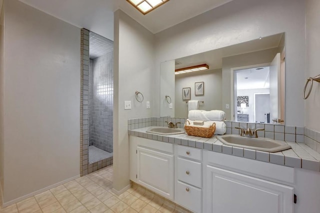 bathroom featuring dual vanity, tile patterned floors, and tiled shower