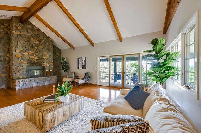 living room featuring beamed ceiling, a stone fireplace, wood-type flooring, and high vaulted ceiling