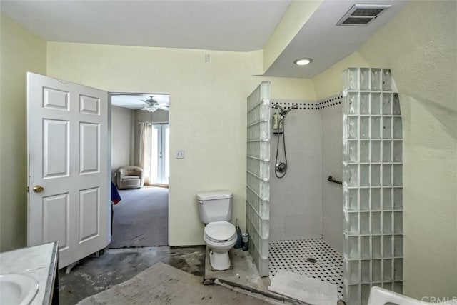 bathroom with ceiling fan, toilet, tiled shower, and vanity