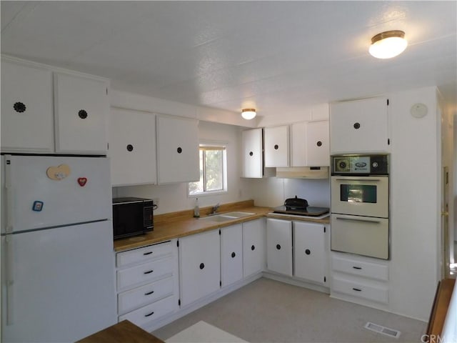 kitchen featuring white appliances, white cabinets, and sink