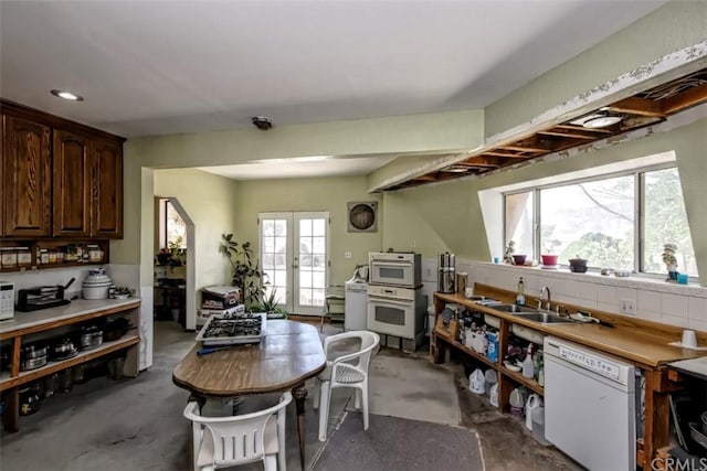 dining room with french doors, sink, concrete floors, and a healthy amount of sunlight