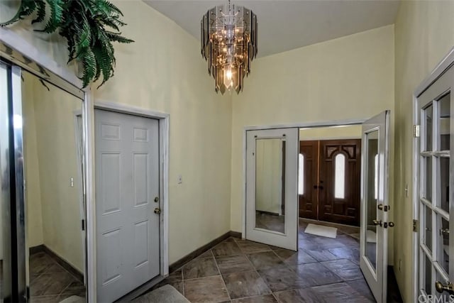 tiled foyer featuring high vaulted ceiling, french doors, a healthy amount of sunlight, and a chandelier