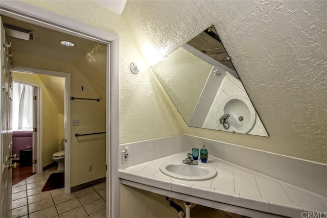 bathroom with sink, tile floors, toilet, and vaulted ceiling