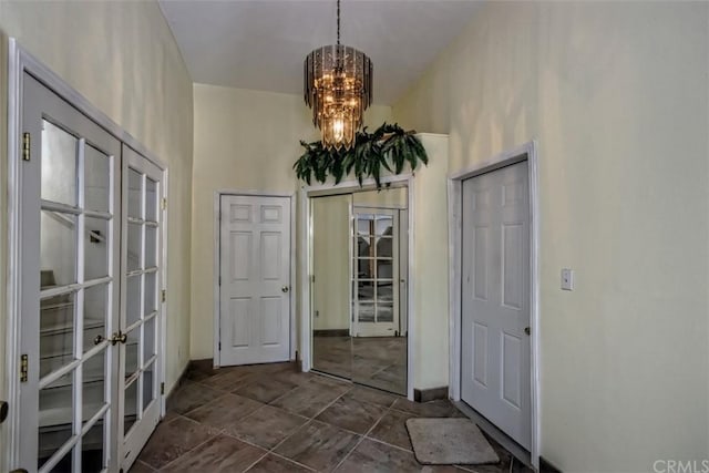 interior space featuring dark tile floors, french doors, and an inviting chandelier