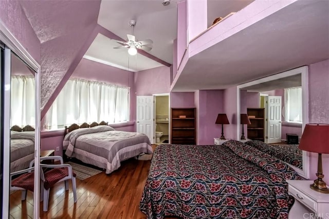 bedroom with ceiling fan, connected bathroom, dark hardwood / wood-style floors, and vaulted ceiling