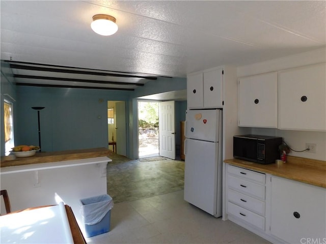 kitchen with white cabinets, a textured ceiling, and white fridge