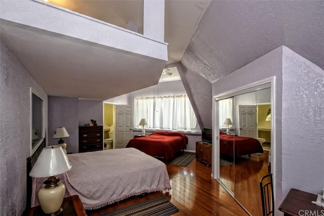 bedroom with dark hardwood / wood-style floors, a textured ceiling, a closet, and lofted ceiling