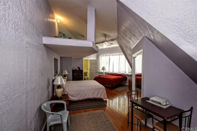 bedroom with lofted ceiling, a textured ceiling, and hardwood / wood-style floors