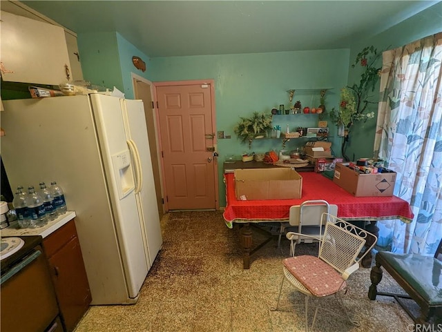 kitchen with white refrigerator with ice dispenser, range, and dark carpet