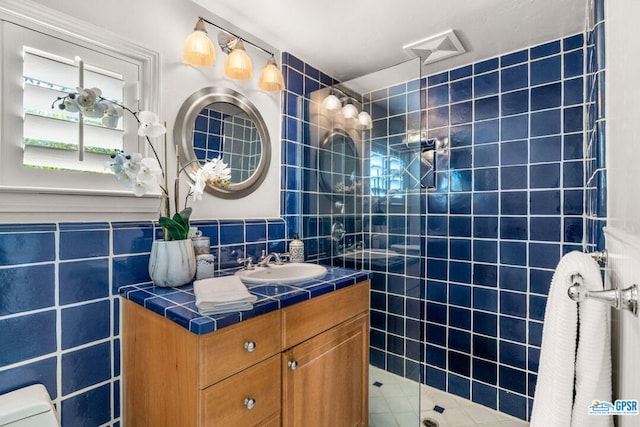 bathroom featuring vanity, toilet, a shower with door, and tile walls