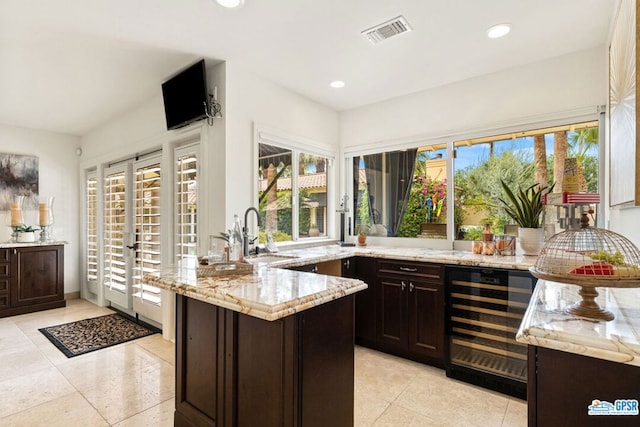 interior space featuring light stone counters, dark brown cabinets, and beverage cooler