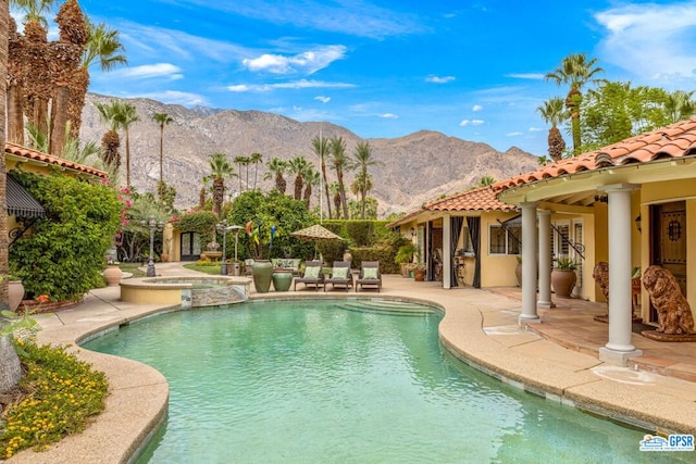 view of pool featuring a mountain view, a patio, and an in ground hot tub