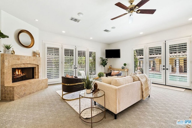 living room featuring a tile fireplace, french doors, and light colored carpet