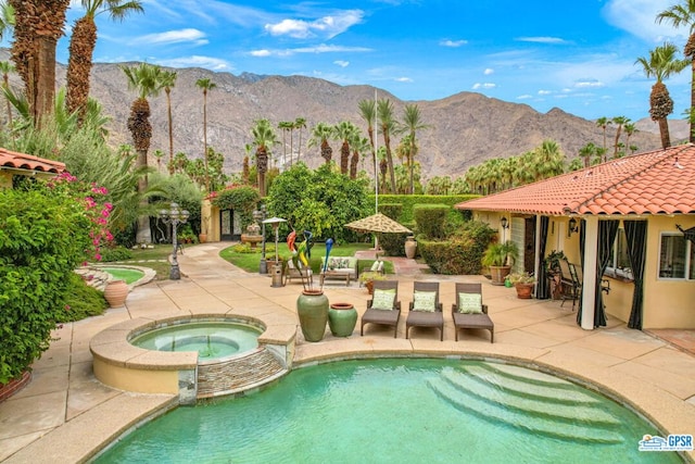 view of swimming pool with an in ground hot tub, a mountain view, and a patio area