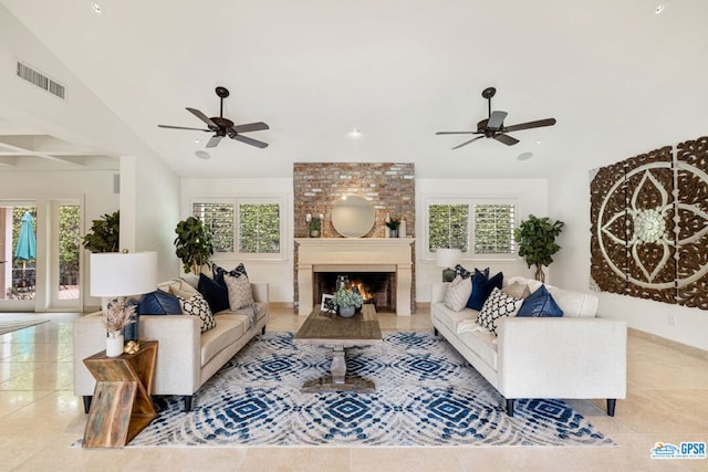 tiled living room with ceiling fan, a large fireplace, a healthy amount of sunlight, and vaulted ceiling