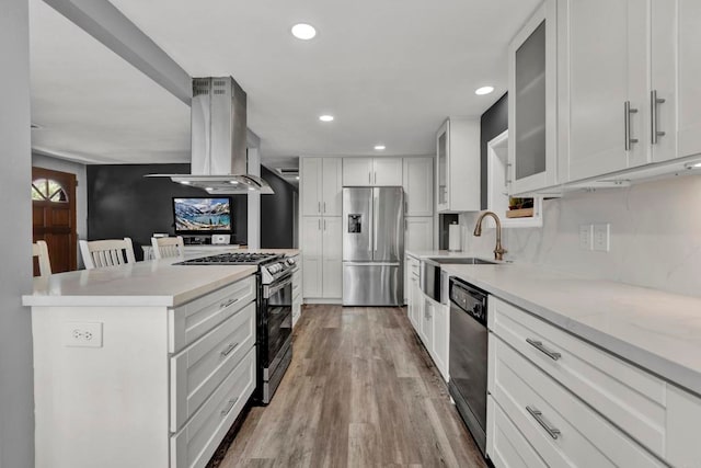 kitchen with a breakfast bar area, stainless steel appliances, glass insert cabinets, white cabinetry, and island range hood