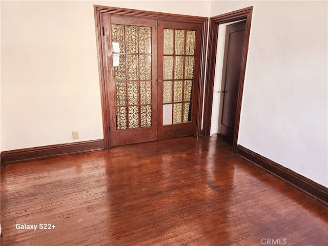 empty room featuring french doors and dark wood-type flooring