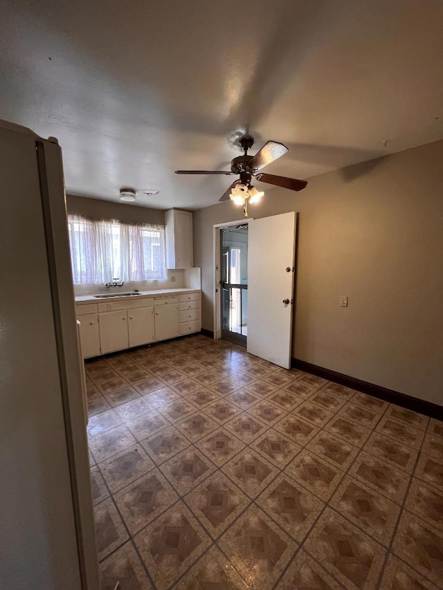 tiled spare room featuring sink and ceiling fan