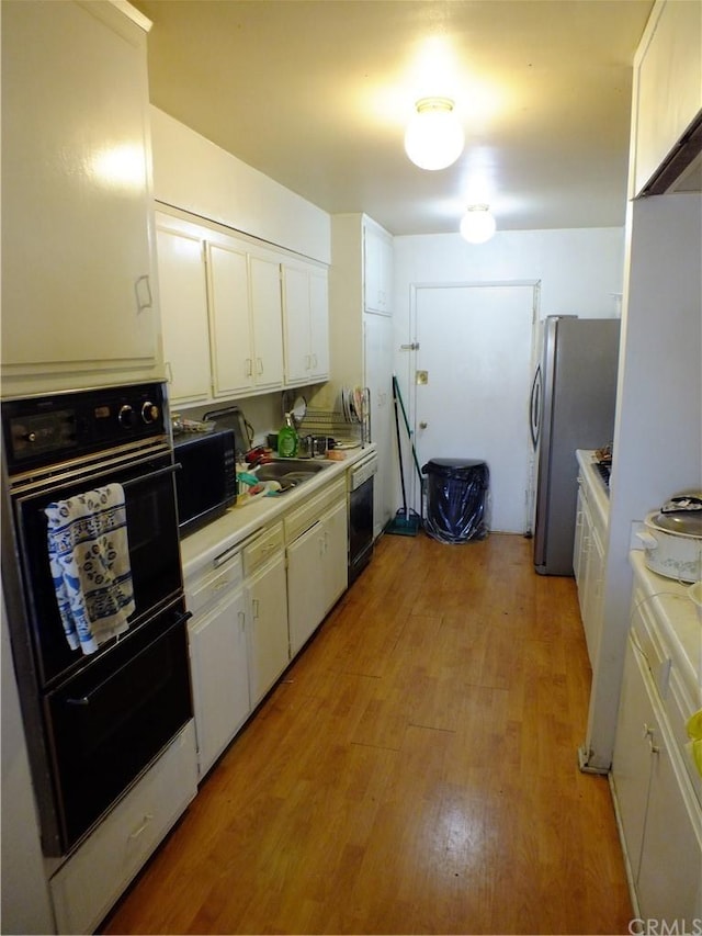 kitchen with stainless steel refrigerator, white cabinets, and light hardwood / wood-style flooring