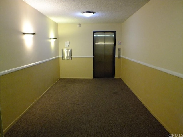 hallway featuring carpet, elevator, and a textured ceiling