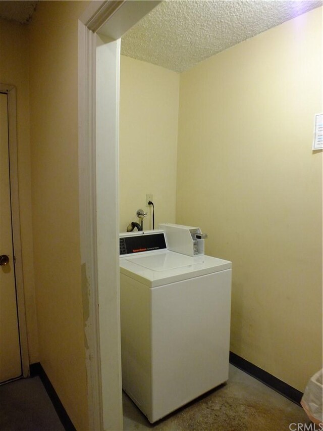 clothes washing area featuring a textured ceiling and washer / clothes dryer