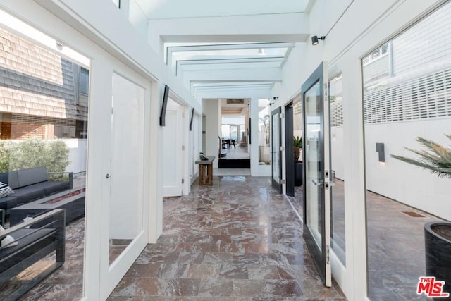 hall with a healthy amount of sunlight, dark tile floors, and french doors