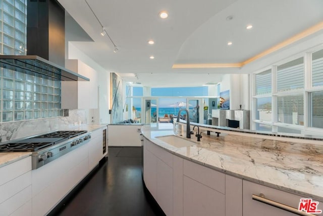 kitchen featuring white cabinets, plenty of natural light, wall chimney exhaust hood, and sink