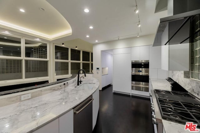 kitchen featuring light stone countertops, white cabinetry, backsplash, appliances with stainless steel finishes, and sink