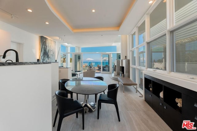 dining space featuring a tray ceiling and light hardwood / wood-style flooring