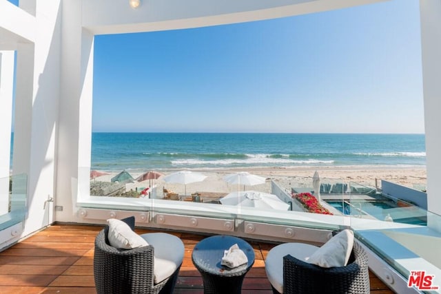 balcony with a water view and a view of the beach