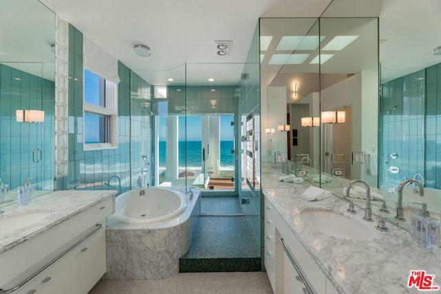 bathroom with double vanity, tiled tub, and a water view