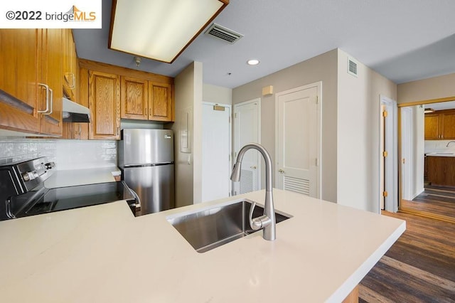 kitchen with decorative backsplash, dark wood-type flooring, sink, range, and stainless steel refrigerator