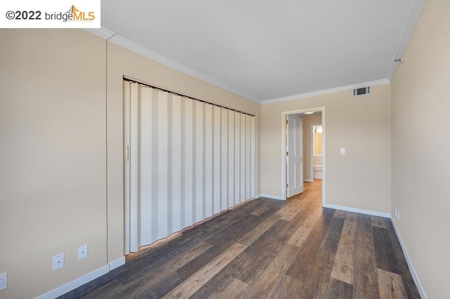 empty room with ornamental molding and dark wood-type flooring