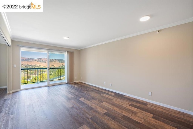 empty room featuring a mountain view, dark hardwood / wood-style flooring, and ornamental molding