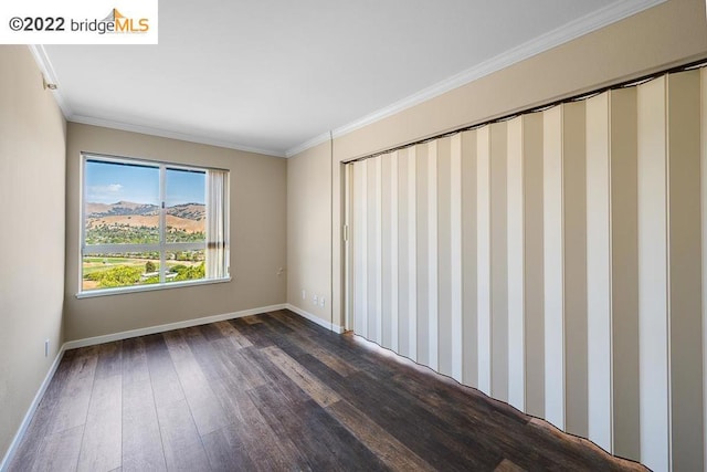 spare room with a mountain view, dark hardwood / wood-style flooring, and ornamental molding