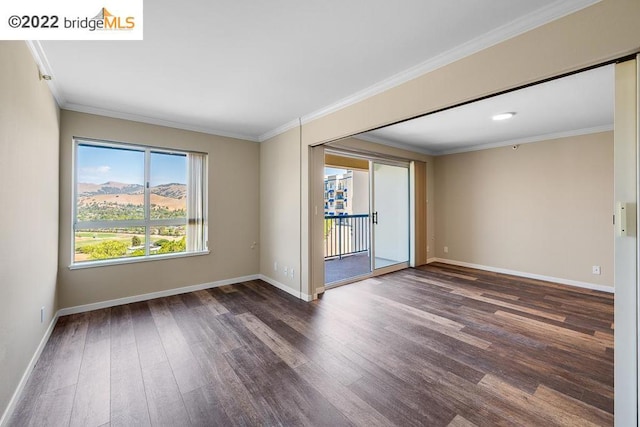 spare room with a mountain view, dark hardwood / wood-style flooring, and crown molding