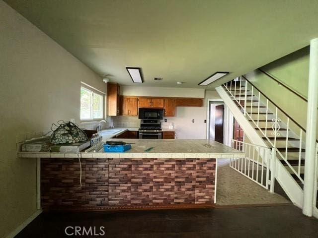 kitchen featuring kitchen peninsula, stainless steel range oven, and sink