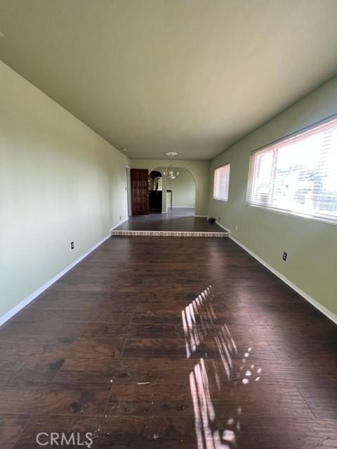 unfurnished living room with an inviting chandelier and dark hardwood / wood-style flooring