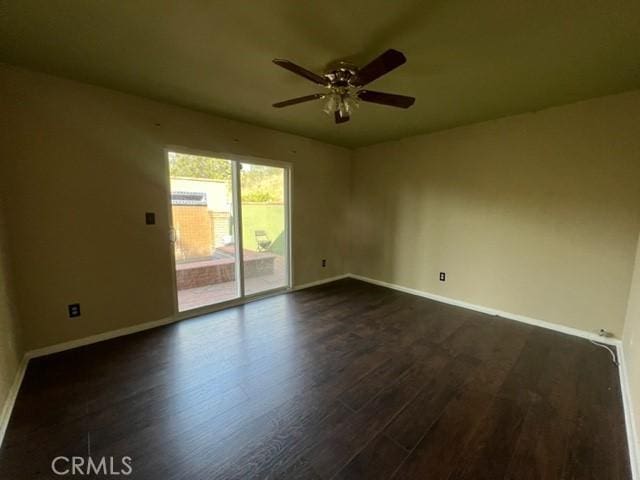 spare room with dark wood finished floors, a ceiling fan, and baseboards