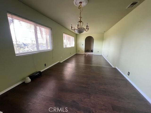 unfurnished dining area featuring dark wood-type flooring and an inviting chandelier